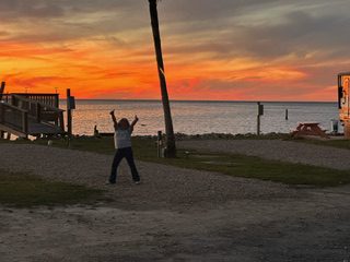 A Person Standing in the Middle of a Road With Palm Trees and a Sunset