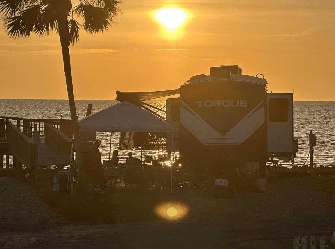 A Camper Parked on a Beach With a Sunset